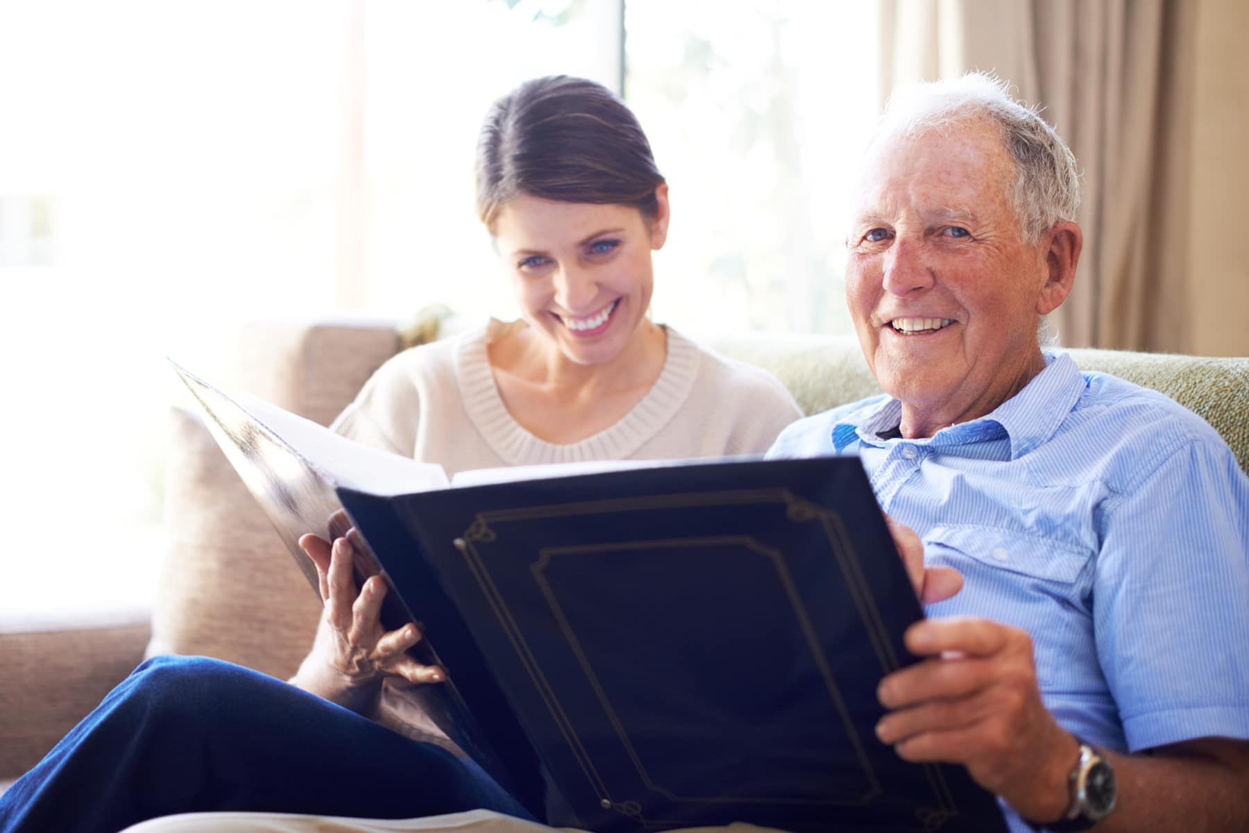 A senior man and his daughter looking at old family photos at the nursing home
